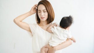 赤ちゃんを抱っこしながらストレスに悩むママ