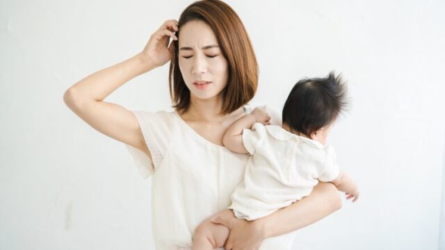 赤ちゃんを抱っこしながらストレスに悩むママ